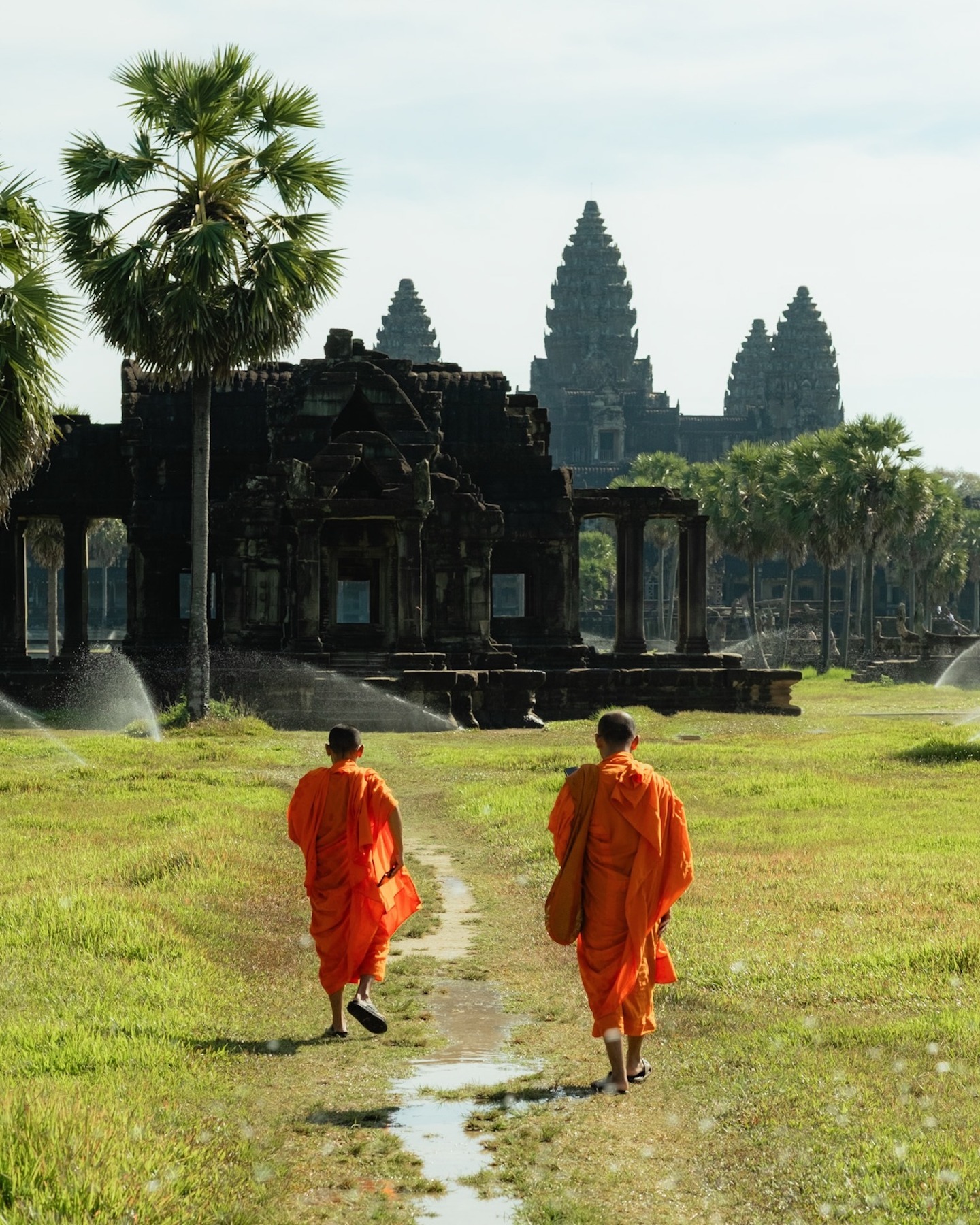 Two Buddhist monks walking towards Angkor Wat temple in Cambodia